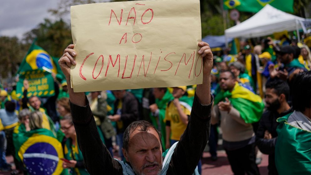 A supporter of Brazilian President Jair Bolsonaro holds a sign that reads in Portuguese: "No to Communism!" during a protest against his defeat in the country's presidential runoff, outside a military base in Sao Paulo, Brazil, Thursday, Nov. 3, 2022