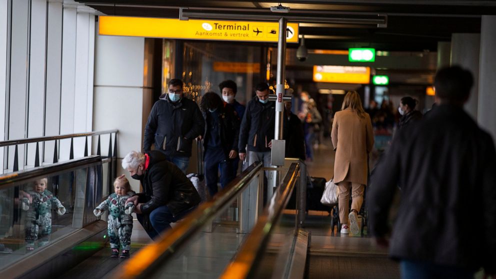 FILE- Arriving and departing passengers use the flat escalators at Schiphol Airport, near Amsterdam, Netherlands, Dec. 18, 2020. Travelers beware: The Netherlands’ busiest airport is reining in flight departures over its busy summer period. That's be