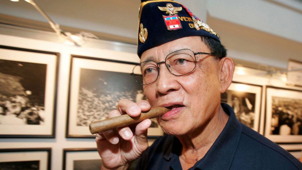 FILE - Former Philippine President Fidel Ramos bites his cigar as he looks on photographs during an exhibit on the 20th anniversary of "People Power" in suburban Makati, south of Manila, Philippines, on Feb. 22, 2006. Ramos, a U.S.-trained ex-general