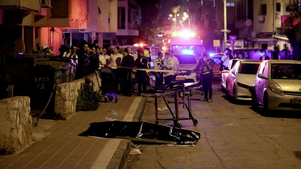 Ultra-Orthodox Jews stand near the covered body of a shooting victim in Bnei Brak, Israel, Tuesday, March 29, 2022. The circumstance of the deadly incident Tuesday were not immediately clear. (AP Photo/Oded Balilty)