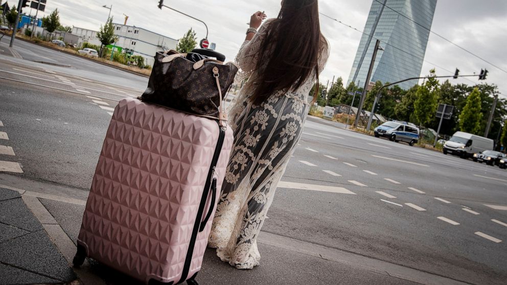 A woman stands with her suitcase near the European Central Bank as 16 000 people are evacuated prior to the defusing of a WWII bomb in Frankfurt, Germany, Sunday, July 7, 2019. The bomb was discovered during construction works right next to the ECB. 
