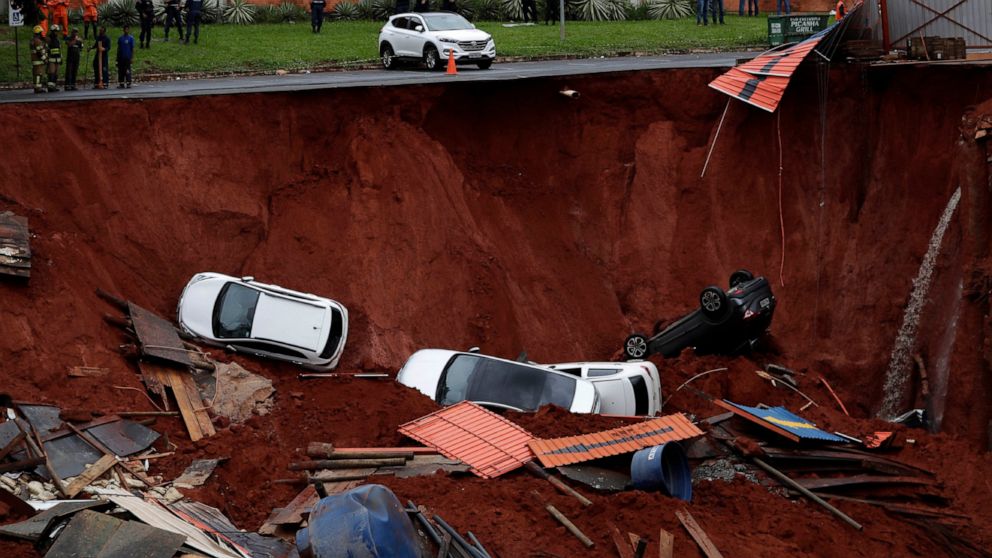Vehicles lay at the bottom of a construction site after they fell in due to a collapse of a road next to it, caused by heavy rains in the center of Brasilia, Brazil, Tuesday, Dec. 10, 2019. There were no victims reported. (AP Photo/Eraldo Peres)