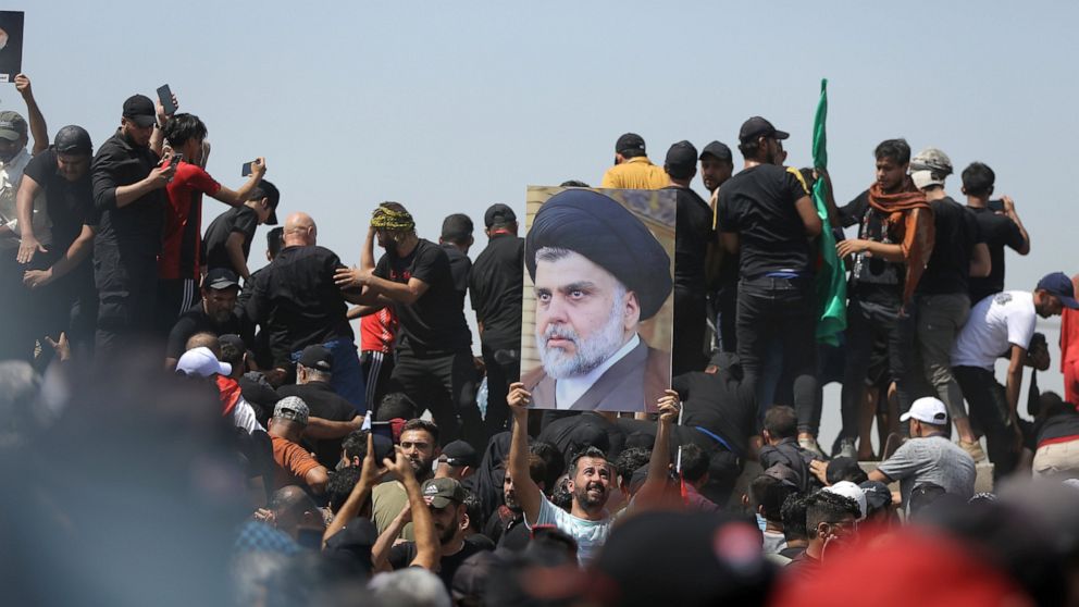 FILE - A protester holds a poster depicting Shiite cleric Muqtada al-Sadr on a bridge leading towards the Green Zone area in Baghdad, Iraq, Saturday, July 30, 2022 — days after hundreds breached Baghdad's parliament Wednesday chanting anti-Iran curse