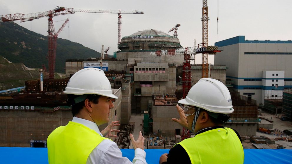 FILE - In this Oct. 17, 2013, file photo, then British Chancellor of the Exchequer George Osborne, left, chats with Taishan Nuclear Power Joint Venture Co. Ltd. General Manager Guo Liming as he inspects a nuclear reactor under construction at the nuc