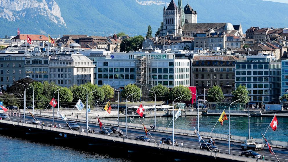 Cars drive on a bridge in front of the old town with the St. Pierre Cathedral in Geneva, Switzerland Monday, June 14, 2021. The lakeside city known as a Cold War crossroads and a hub for Swiss discretion, neutrality and humanitarianism, is set to ret