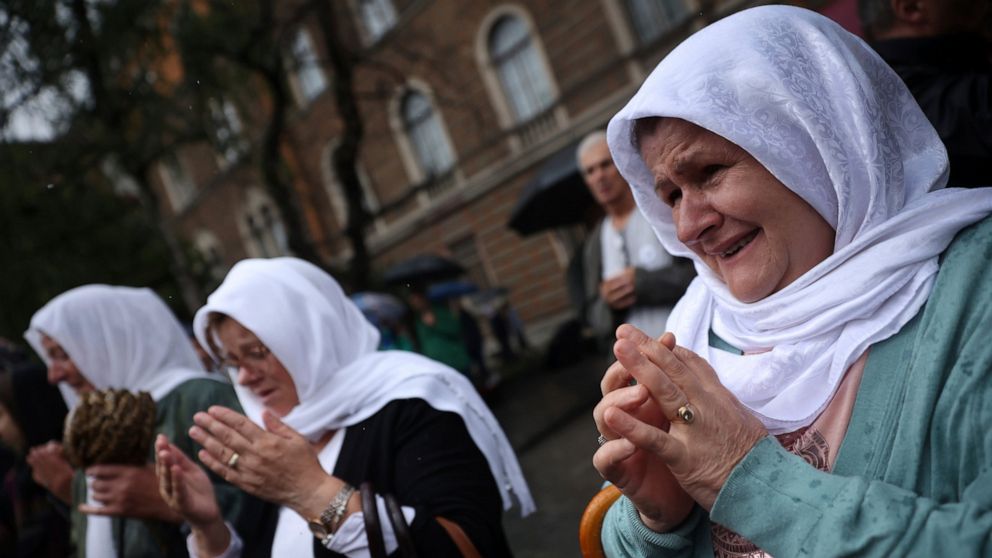Women pray next to the truck carrying 50 coffins with remains of the victims of the 1995 Srebrenica genocide in Sarajevo, Bosnia, Friday, July 8, 2022. The remains of the 50 recently identified victims of Srebrenica Genocide will be transported to th