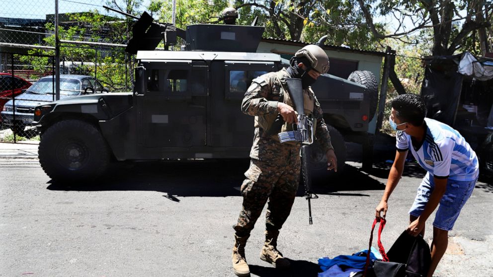 A soldier checks a man´s backpack at the exit of the Las Palmas Community, a neighborhood that is supposed to be under the control of the Barrio 18 Gang in San Salvador, El Salvador, Sunday, March 27, 2022. El Salvador's congress has granted Presiden
