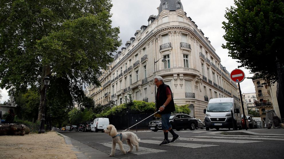 FILE - In this Aug.13, 2019 file photo, a man walks his dog next to an apartment building owned by Jeffrey Epstein in the 16th district in Paris, Tuesday, Aug. 13, 2019. Women who claim they were raped and sexually assaulted by an associate of Jeffre