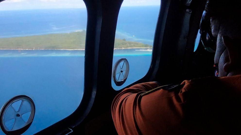 In this photo released by South Sulawesi Search and Rescue Agency (BASARNAS Sulawesi Selatan), members of rescue team look out of the windows of a helicopter during a search flight for a sinking ferry over Makassar Strait, Indonesia, Sunday, May 29, 