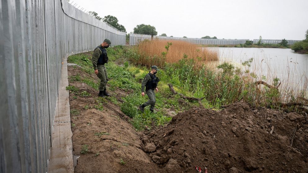 FILE - In this Friday, May 21, 2021, policemen patrol alongside a steel wall at Evros river, near the village of Poros, at the Greek - Turkish border, Greece. Greece says it will renew a request for European Union funds in 2022 to extend a border wal