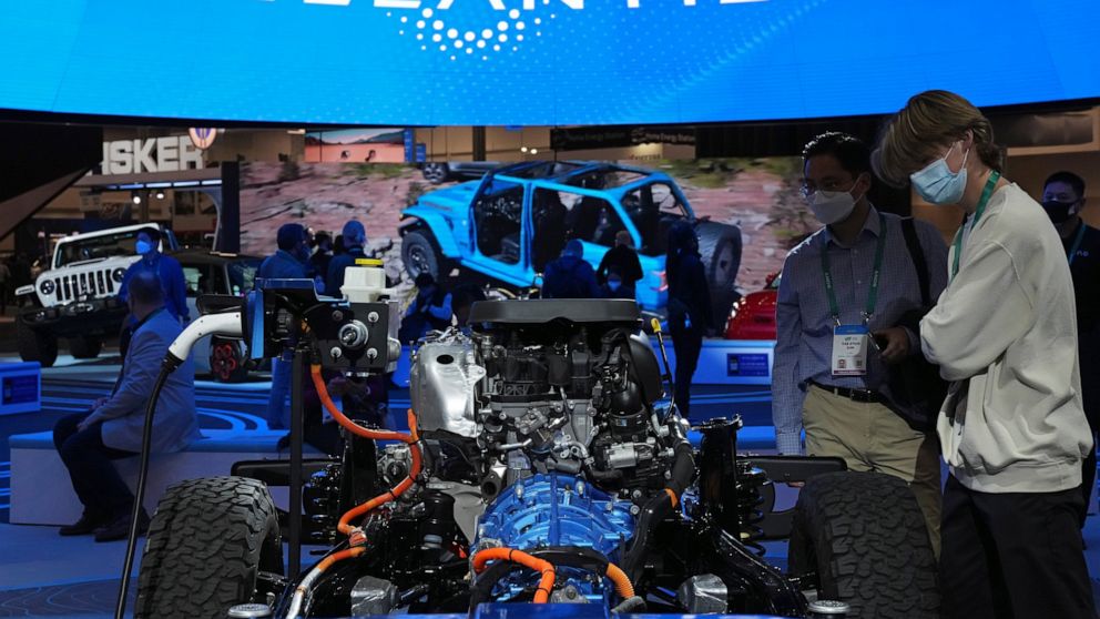 FILE - People look at the charging technology from the Jeep Wrangler 4xe at the Stellantis booth during the CES tech show Thursday, Jan. 6, 2022, in Las Vegas. Automaker Stellantis said Wednesday, Feb. 23, 2022 that it made 13.4 billion euros ($15.2 