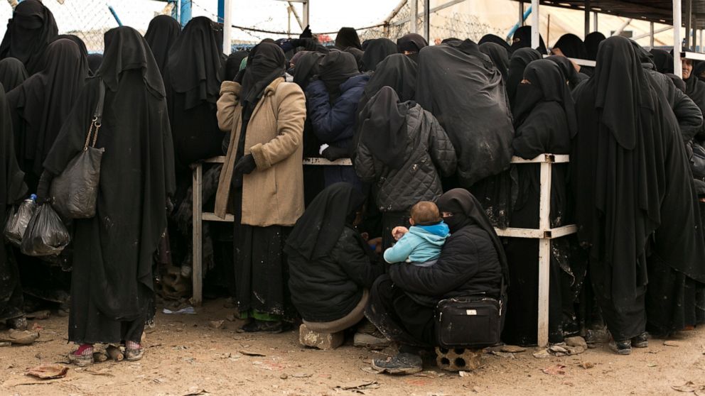 FILE - In this March 31, 2019 file, photo, women residents from former Islamic State-held areas in Syria line up for aid supplies at Al-Hol camp in Hassakeh province, Syria. Killings have surged inside the camp with at least 20 men and women killed i