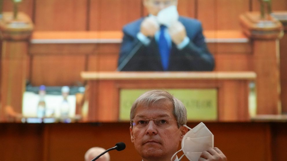 Romanian Prime Minister designate Dacian Ciolos removes his mask before addressing a parliament session, in Bucharest, Romania, Wednesday, Oct. 20, 2021. (AP Photo/Vadim Ghirda)