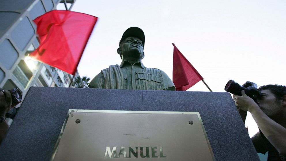 FILE - In this Sept. 26, 2008 file photo, photographers take pictures of a bust of the late Manuel Marulanda, the founding leader of the Revolutionary Armed Forces of Colombia, or FARC, unveiled by members of the Venezuela's Communist Party in a plaz