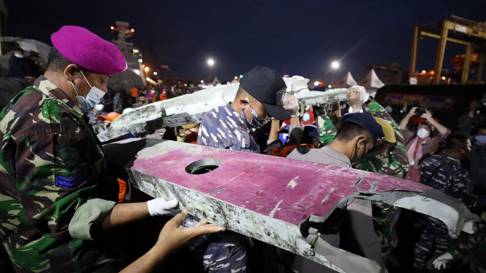 Soldiers and rescue personnel carry debris found in the waters off Java Island around where a Sriwijaya Air passenger jet crashed on Saturday, at Tanjung Priok Port in Jakarta, Indonesia, Sunday, Jan. 10, 2021. Indonesian rescuers pulled out body par