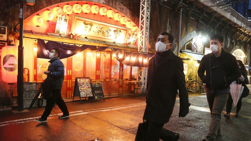 People wearing face masks to help protect against the spread of the coronavirus walk along a street lined with bars and restaurants in Tokyo, Tuesday, March 22, 2022. Pre-emergency measures to prevent the Covid-19 outbreak have been lifted. (AP Photo
