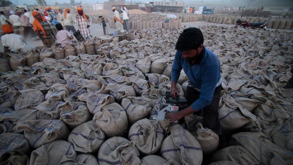 FILE - A laborer seals sacks filled with wheat in Gurdaspur, in the northern Indian state of Punjab, April 30, 2014. (AP Photo/Channi Anand, File)