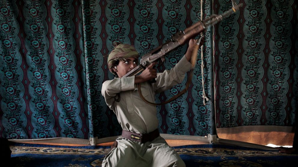 FILE - Kahlan, a 12-year-old former child soldier, demonstrates how to use a weapon, at a camp for displaced persons where he took shelter with his family, in Marib, Yemen, July 27, 2018. emen’s Houthi rebels continue to recruit children into their m