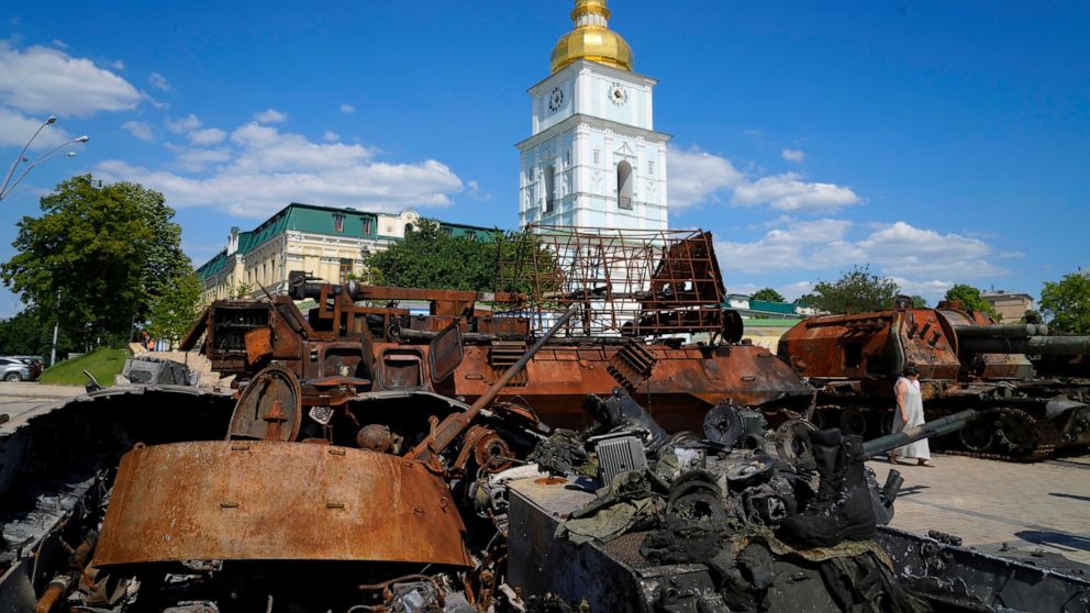 FILE - A woman walks by destroyed Russian tanks installed as a symbol of war in front of St Michael cathedral, in central Kyiv, Ukraine, Tuesday, June 7, 2022. Polish and Ukraine government officials say that Russian tanks and armored vehicles damage
