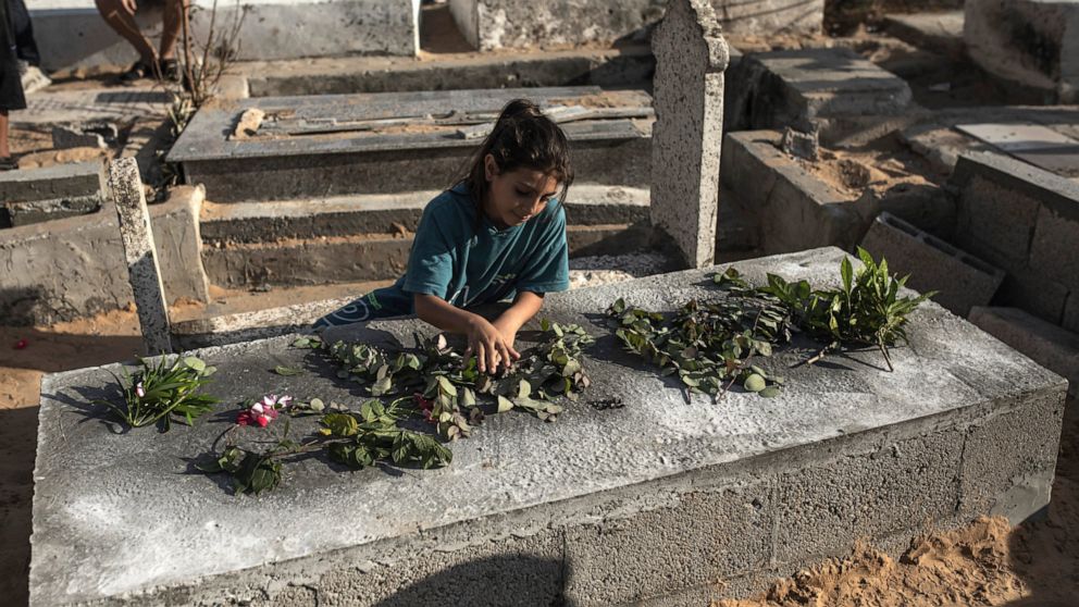 A Palestinian girl lays roses on the grave of one of the children of Nijim family at Al-Faluja cemetery in Jabalia in the northern Gaza Strip, Tuesday, Aug. 16, 2022. A Palestinian human rights group and an Israeli newspaper reported Tuesday that an 