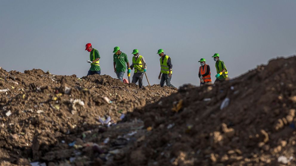Workers walk to collect clothes and other materials, under the instruction of investigators, at the scene where the Ethiopian Airlines Boeing 737 Max 8 crashed shortly after takeoff on Sunday killing all 157 on board, near Bishoftu, or Debre Zeit, so