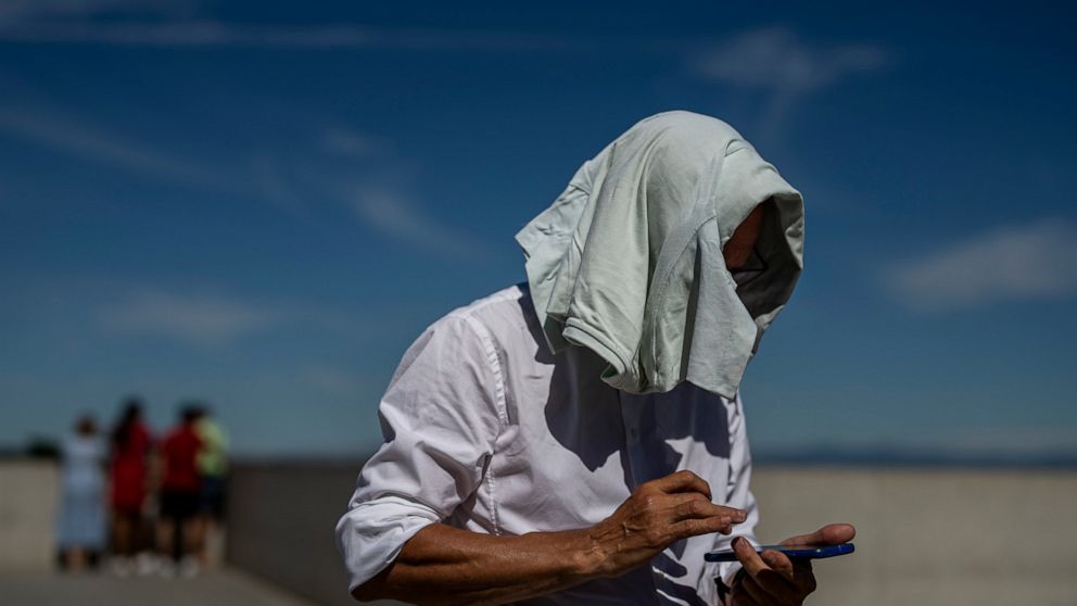 A man covers his head from the sun on a hot day in Madrid, Spain, Friday, June 10, 2022. Temperatures are rising with predictions that it will reach over 40 degrees Celsius (104 degrees Fahrenheit) by the weekend in some parts of Spain. (AP Photo/Man