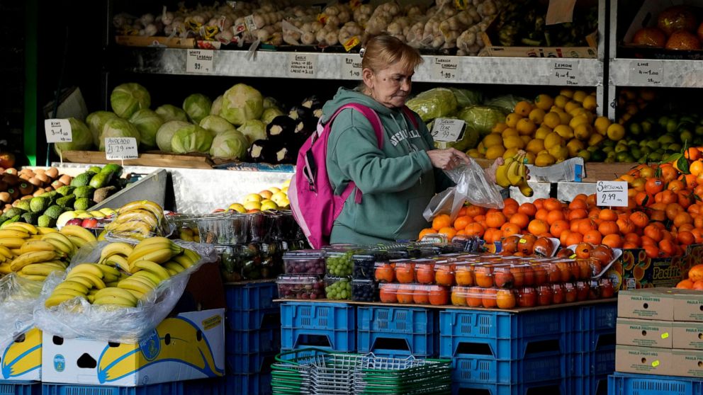 FILE - A woman selects fruits at a supermarket in London, Wednesday, Nov. 17, 2021. The Office for National Statistics said Wednesday, Aug. 17, 2022, that consumer prices inflation hit double digits, a jump from 9.4% in June and higher than analysts’