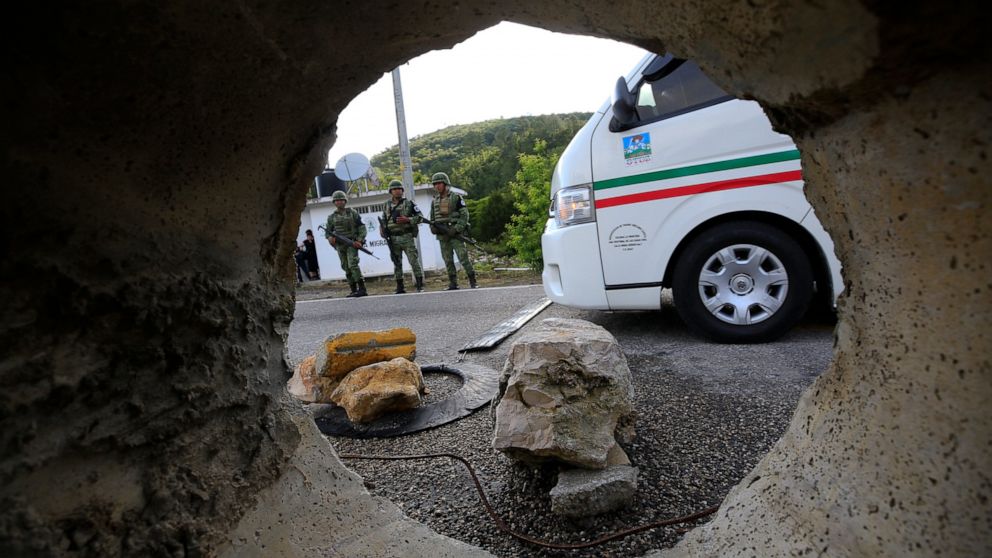 Seen through a section of pipe placed the middle of a road between two-way traffic, soldiers forming part of the National Guard stand guard at an immigration checkpoint heading north out of Comitan, Chiapas state, Mexico, Sunday, June 16, 2019. Mexic