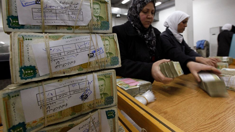 FILE - This January 13, 2010 file photo, employees stack Syrian currency in the Central Bank, in Damascus, Syria. The Syrian pound has crashed to its lowest levels in recent days against the U.S. dollar leading to increase in prices in the war-torn c