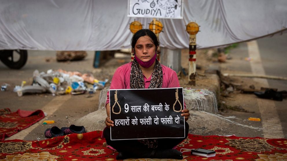 Tina Verma, 27, a social activist, holds a placard which reads, "Hang the killers of 9-year old child" at a demonstration site outside a crematorium where a 9-year-old girl from the lowest rung of India's caste system was, according to her parents an