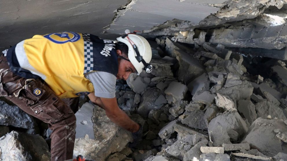This photo posted and provided by the Syrian Civil Defense White Helmets, which has been authenticated based on its contents and other AP reporting, shows a Civil Defense worker searching for victims under the rubble after an airstrike by Syrian gove