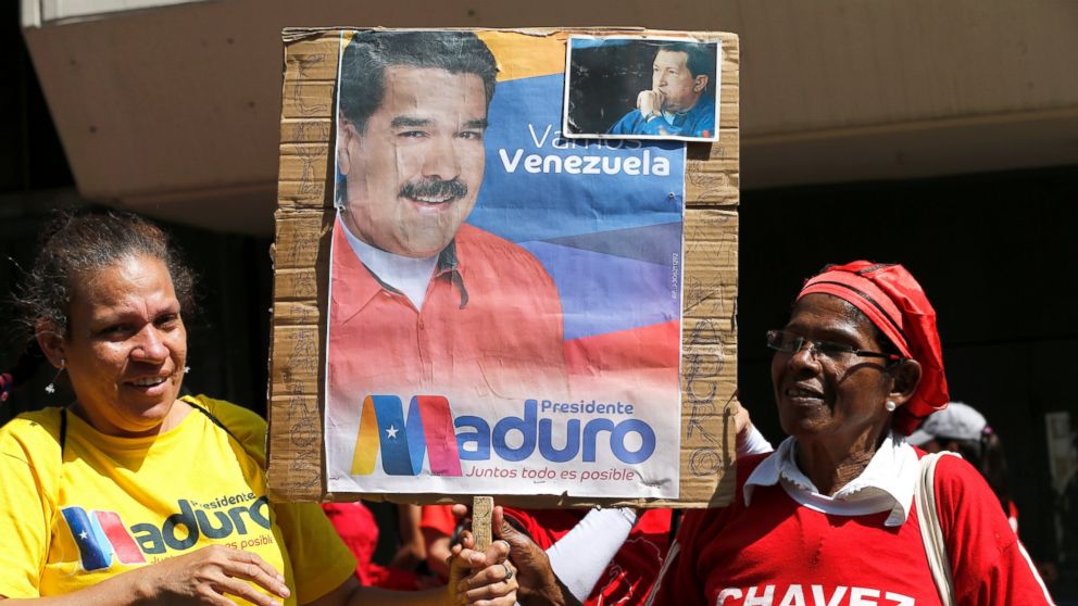 Supporters of Venezuela's President Nicolas Maduro hold a poster of him outside the Supreme Court where he is being sworn-in for another term in Caracas, Venezuela, Thursday, Jan. 10, 2019. Maduro was sworn in to a second term amid international call