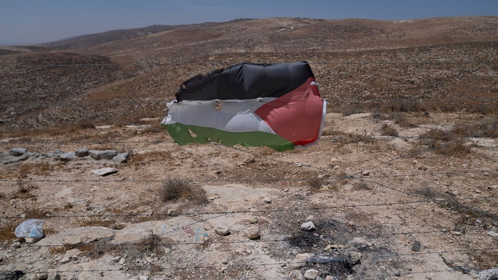 A Palestinian flag is posted at a barbed wired at the Palestinian hamlet of Khallat al-Dhaba, in the cluster of Bedouin communities in Masafer Yatta, West Bank, Monday, Aug. 1, 2022. Palestinians living in Masafer Yatta, in the occupied West Bank, fe