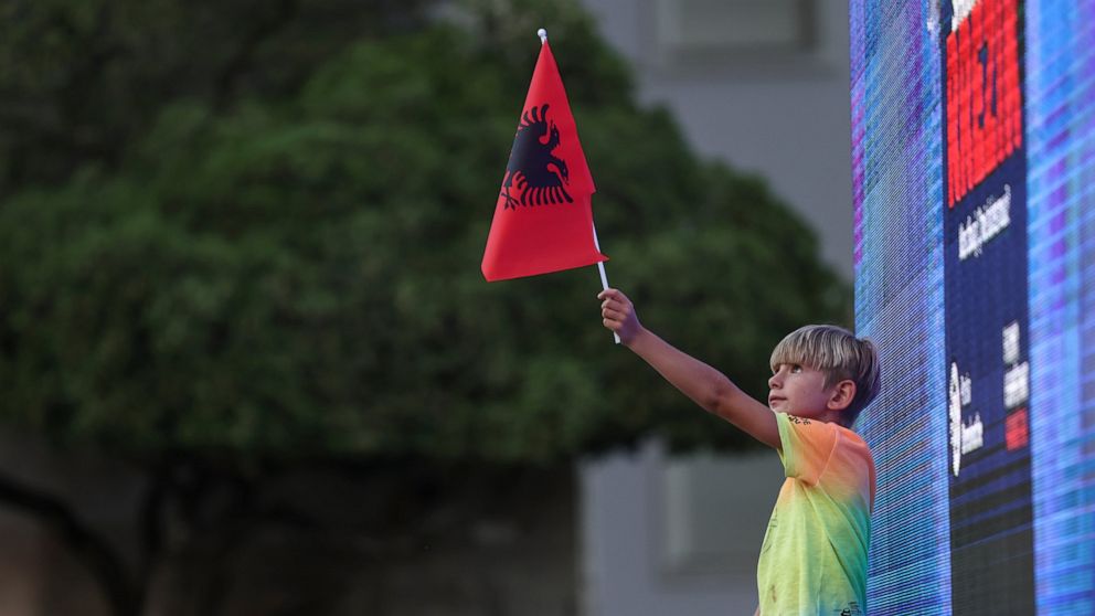 A boy holds an Albanian flag outside the Prime Minister's office during an anti-government rally in Tirana, Albania, on Thursday, July 7, 2022. The Albanian opposition rallied Thursday in the capital Tirana calling for the resignation of the governme