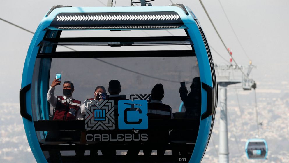 Officials take pictures as they ride in a cable car between the Campos Revolucion and Tlalpexco stations, during the inauguration of a new aerial public transit system dubbed the Cablebus, in the Cuautepec neighborhood of northern Mexico City, Thursd