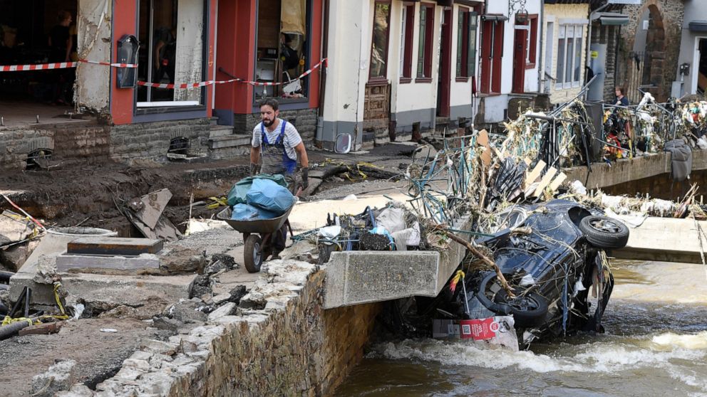 A man helps with the cleanup by carrying rubbish and debris after heavy rain and flooding along the Erft in Bad Münstereifel, Germany, Saturday, July 17, 2021. On the night of July 15, the Erft floods totally devastated the historic core of the city 