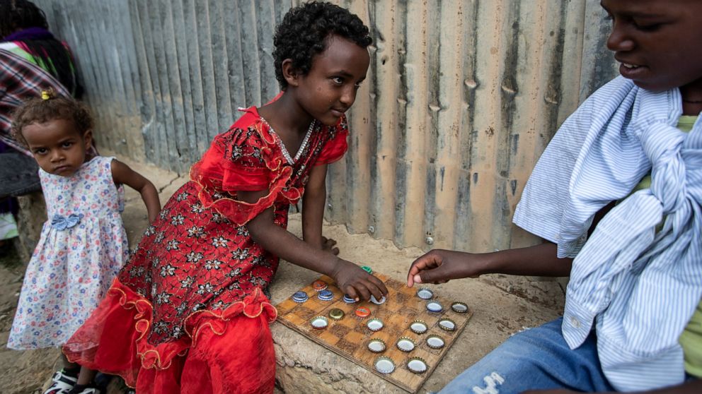 Elena, 7, left, plays a game of checkers using soda bottle tops with friend Hailemariam, 12, at a reception and day center for displaced Tigrayans in Mekele, in the Tigray region of northern Ethiopia, Sunday, May 9, 2021. The Tigray conflict has disp