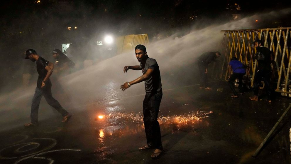Protestors run for cover as police fire tear gas shells near the president's official residence in Colombo, Sri Lanka, Saturday, May 28, 2022. Police fired tear gas and water canon on protesters who marched toward the president Gotabaya Rajapaksa's b