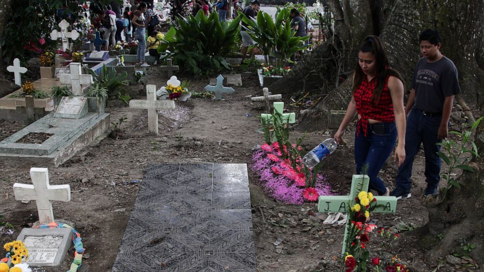 A couple walks next to one of the graves of gang members whose tombstone was destroyed on order of the government, during the Day of the Dead at the Nueva San Salvador Cemetery, in Santa Tecla, El Salvador, Wednesday, Nov. 2, 2022. Santa Tecla Mayor 