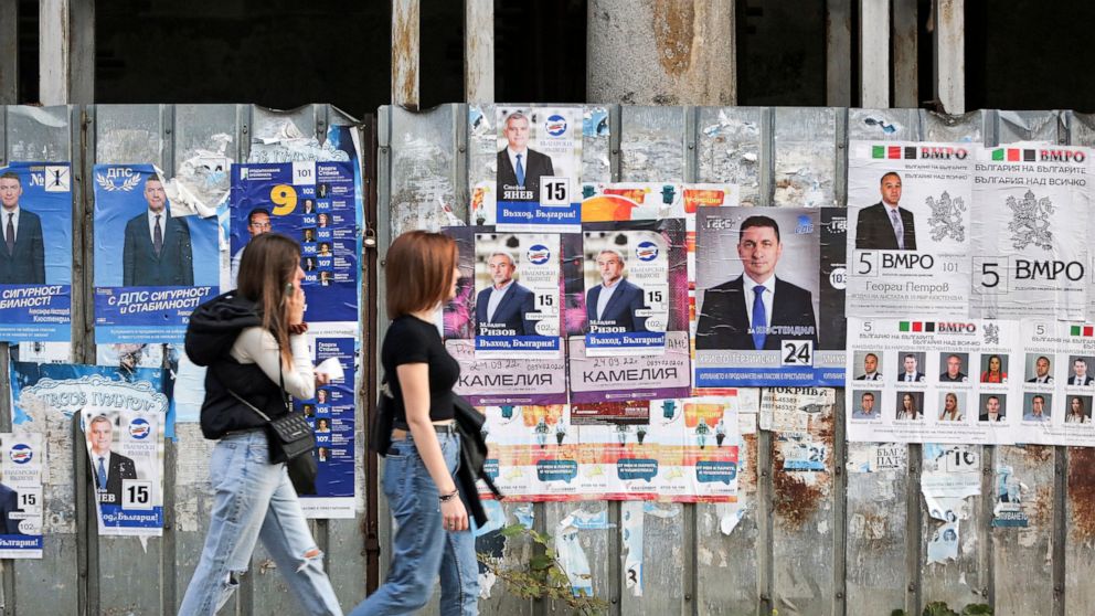Women walk past election campaign posters in Kyustendil, Bulgaria, Thursday, Sept. 29, 2022. Bulgarians will go to the polls for the fourth time in less than two years, in a general election overshadowed this time by the war in Ukraine, the rising en