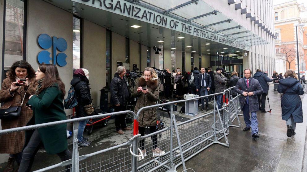 FILE - In this Friday March 6, 2020 file photo, people stand outside the headquarters of the Organization of the Petroleum Exporting Countries, OPEC, in Vienna, Austria. Members of the OPEC oil producing cartel and allied countries led by Russia sign