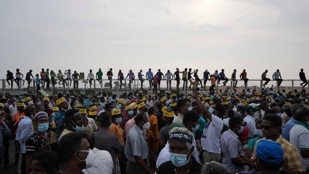 Supporters of Sri Lanka's main opposition sit on the fence of the Chinese owned Port City project as they gather a protest outside the president's office in Colombo, Sri Lanka, Tuesday, March 15, 2022. The protestors were demanding the resignation of