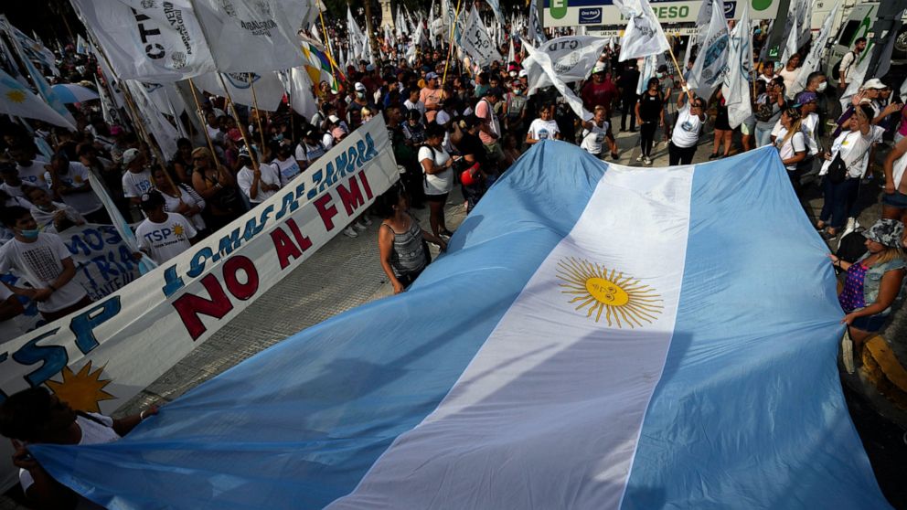 People display an Argentine national flag during a protest outside Congress as senators prepare to vote on a law to ratify the government’s agreement with the IMF to refinance some $45 billion in debt, in Buenos Aires, Argentina, Thursday, March 17, 