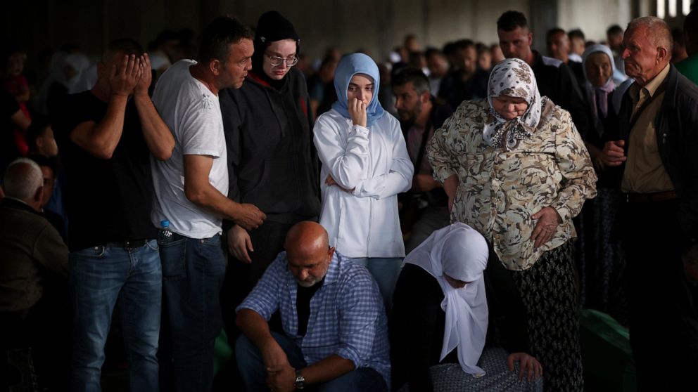 Muslim men and women pray next to the coffins of their relatives, victim of the 1995 Srebrenica genocide in Potocari, Bosnia, Friday, July 8, 2022. The remains of the 50 recently identified victims of Srebrenica massacre, Europe’s only acknowledged g