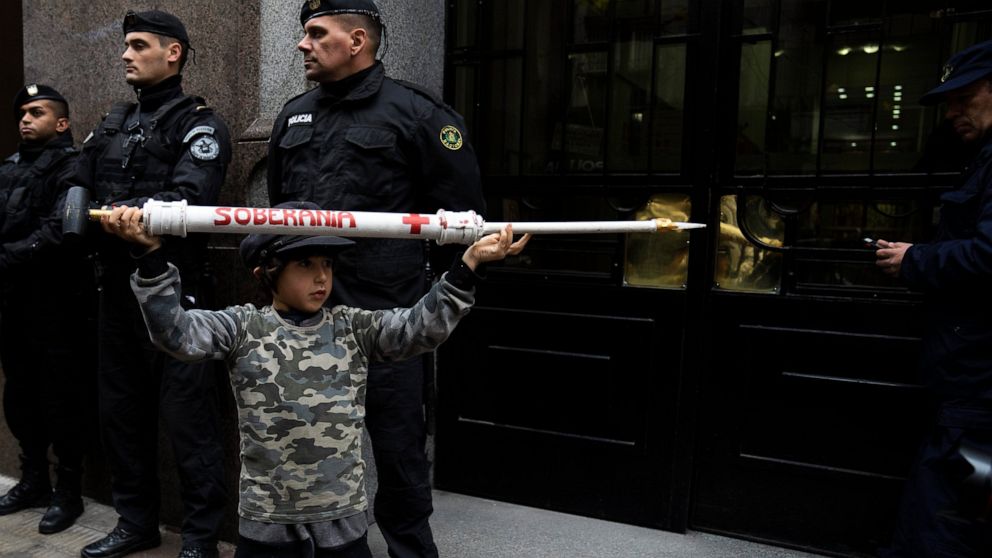 A boy holding a giant, mock syringe that reads in Spanish "sovereignty" attends a protest outside the Supreme court during a hearing where the government and Pfizer are to give more detailed information on COVID-19 vaccines for children, which was re