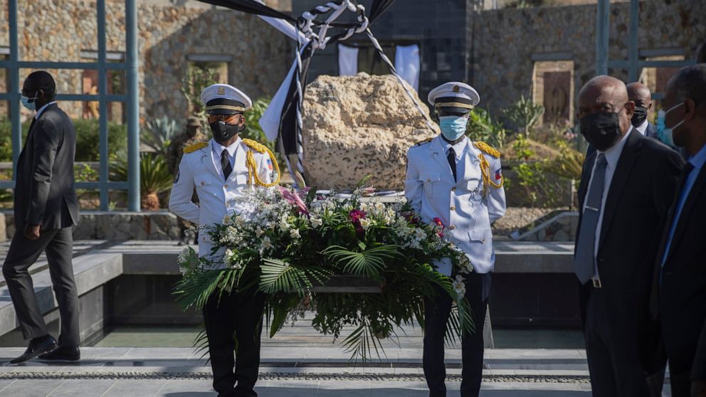 National police officers holding a flower wreath wait for the arrival of Haitian Prime Minister Ariel Henry for a memorial service for victims of the 2010 earthquake, at Titanyen, a mass burial site north of Port-au-Prince, Haiti, Wednesday, Jan. 12,