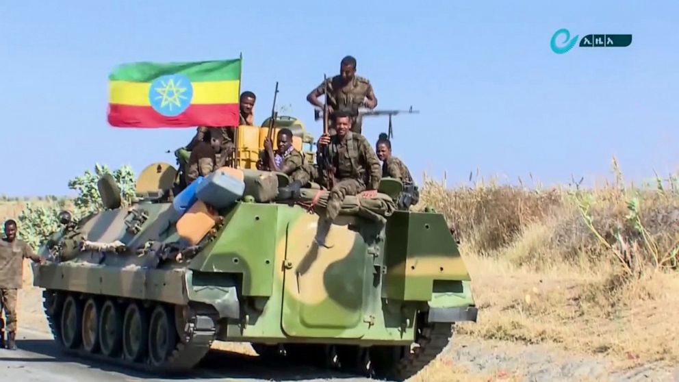 This image made from undated video released by the state-owned Ethiopian News Agency on Monday, Nov. 16, 2020 shows Ethiopian military sitting on an armored personnel carrier next to a national flag, on a road in an area near the border of the Tigray