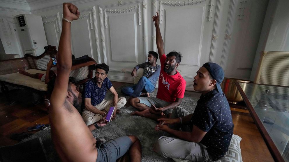 Protesters shout slogans as they stay and play cards in prime minister's official residence a day after it was stormed in Colombo, Sri Lanka, Sunday, July 10, 2022. Sri Lanka’s president and prime minister agreed to resign Saturday after the country’