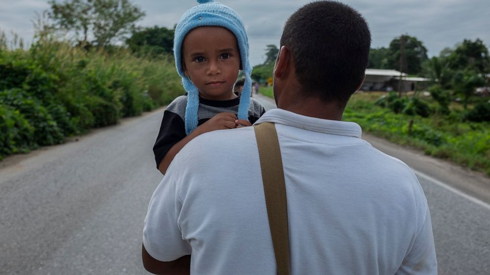 Haitian migrant Yoel eyes the camera as he is carried by his father in Jesus Carranza, in the Mexican state of Veracruz, Wednesday, Nov. 17, 2021. A group of mainly Central American migrants are attempting to reach the U.S.-Mexico border. (AP Photo/F