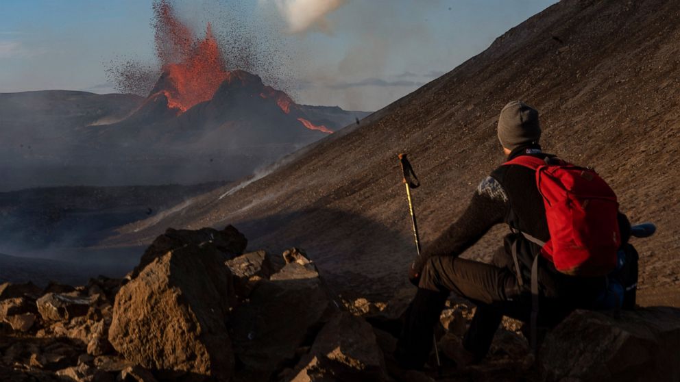 A man watches as lava spews from an eruption of the Fagradalsfjall volcano on the Reykjanes Peninsula in southwestern Iceland on Tuesday, May 11, 2021. (AP Photo/Miguel Morenatti)